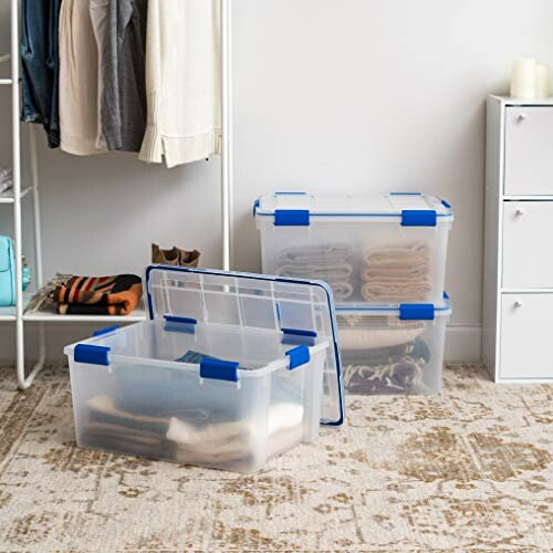 Clear storage boxes in a closet with clothes and shoes.