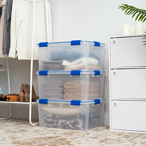 Stacked transparent storage boxes with clothes near a closet.